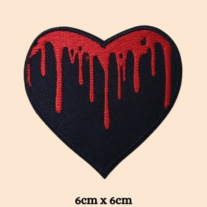 May include: Black heart-shaped patch with red dripping paint. The patch is 6 cm by 6 cm.