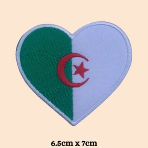 May include: A heart-shaped embroidered patch with the flag of Algeria. The patch is green and white with a red crescent moon and star in the center. It measures 6.5 inches by 7 inches.