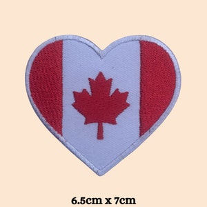 May include: Red and white heart-shaped patch with the Canadian flag design. The flag features a red maple leaf on a white background with red stripes on the sides. The patch measures 6.5 inches by 7 inches.