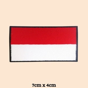 May include: A red and white embroidered patch of the Indonesian flag with a black border. The patch measures 7 inches by 4 inches.