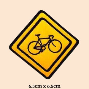 Könnte beinhalten: Gelbes, rautenförmiges Warnschild mit schwarzem Rand und einer schwarzen Silhouette eines Fahrrads im Inneren. Das Schild misst 6,5 cm x 6,5 cm.