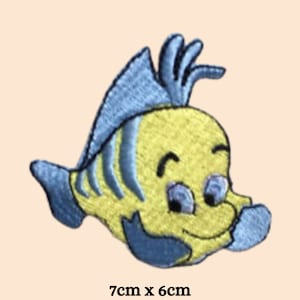 Puede incluir: Un parche bordado para planchar de un pez de dibujos animados con una cara sonriente. El parche es amarillo y azul y mide 7 cm por 6 cm.