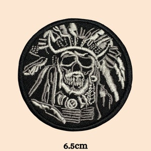 Peut inclure: Patch brodé noir et blanc d'un crâne portant une coiffe avec des plumes. Le patch mesure 6,5 cm de diamètre.