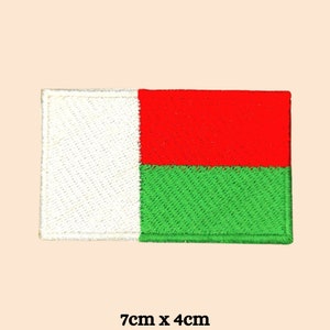 Puede incluir: Parche bordado con la bandera de Madagascar. El parche rectangular está dividido en tres secciones verticales: una sección blanca a la izquierda, una sección roja en la parte superior y una sección verde en la parte inferior. Mide aproximadamente 7 cm x 4 cm.