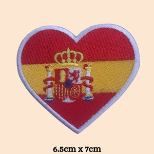 May include: Red, yellow, and white embroidered heart-shaped patch with the Spanish flag and coat of arms. The patch measures 6.5 inches by 7 inches.