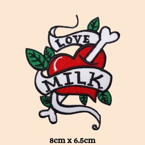 以下が含まれることがあります： 緑の葉と「LOVE MILK」と書かれた白いバナーで囲まれた、白い骨が突き刺さった赤いハート。パッチのサイズは8cm×6.5cmです。