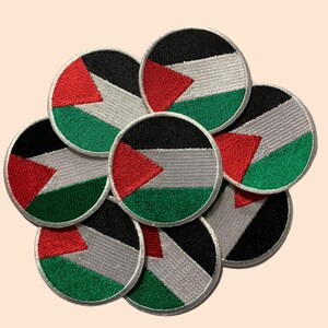 May include: A group of eight round embroidered patches featuring the Palestinian flag. The patches are red, white, black, and green.