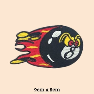 May include: A black and white 8-ball with a cartoon face is on fire. The flames are red and yellow. The patch is 9 cm by 5 cm.