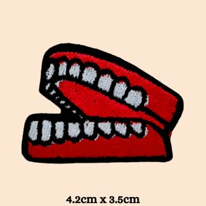 May include: Red and white embroidered iron-on patch of a set of dentures. The patch measures 4.2 cm by 3.5 cm.