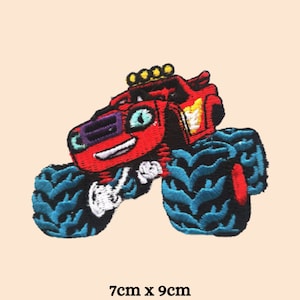 May include: Red monster truck with blue tyres and a smiling face. The truck has a yellow light bar on top and is 7cm x 9cm.