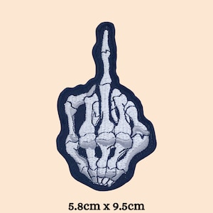 May include: A white skeleton hand giving the middle finger. The hand is outlined in dark blue and is 5.8 inches by 9.5 inches.