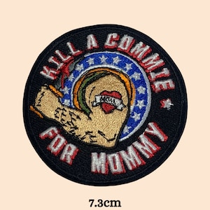 May include: Round embroidered patch with the text "KILL A COMMIE FOR MOMMY" in red and white. The patch features a muscular arm with a heart tattoo that says "MOM". The patch is 7.3cm in diameter.