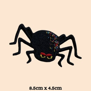 Op de afbeelding: Zwarte geborduurde spinnenpatch met kleurrijke details. De spin heeft acht poten en rode ogen. De patch is 8,5 cm bij 4,5 cm.