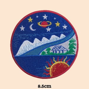 May include: Embroidered iron-on patch with a blue, white, and red design. The patch features a night sky with stars, a crescent moon, a planet, and mountains. The bottom of the patch shows a red sun with yellow rays and a small house.