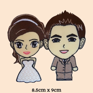Puede incluir: Parche bordado de una novia y un novio de dibujos animados. La novia lleva un vestido blanco y el novio lleva un traje marrón. El parche mide 8,5 cm por 9 cm.