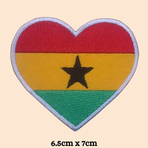 May include: A heart-shaped embroidered patch with the flag of Ghana. The flag is red, yellow, green, and black with a black five-pointed star in the center. The patch measures 6.5 cm by 7 cm.