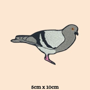 May include: Embroidered patch featuring a pigeon in grey, black, and white, with a pink foot and orange eye. The patch measures 5cm x 10cm.