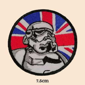 Può includere: Una toppa rotonda ricamata con un casco di Stormtrooper bianco su uno sfondo di bandiera britannica. La toppa ha un diametro di 7,5 cm.