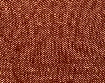May include: A close-up of a red fabric with a woven diamond pattern in a lighter shade of orange.