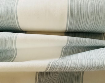 May include: Close-up of a folded fabric with a striped pattern. The fabric features alternating bands of off-white and light gray stripes. The texture of the fabric is visible, with a slightly wrinkled appearance.