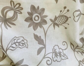 May include: Close-up of off-white fabric with embroidered floral patterns in shades of taupe. The design features stylized flowers, leaves, and stems, creating a delicate and textured appearance. The embroidery adds depth and visual interest to the fabric.
