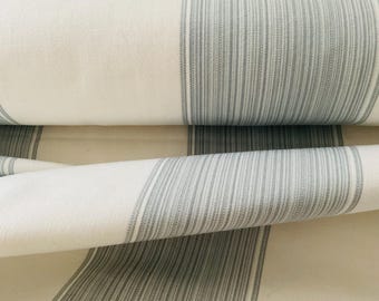 May include: Close-up of a folded fabric with a white background and vertical gray stripes. The fabric is rolled and layered, showcasing the texture and pattern. The stripes are evenly spaced, creating a classic, clean design. The fabric appears to be cotton or linen.