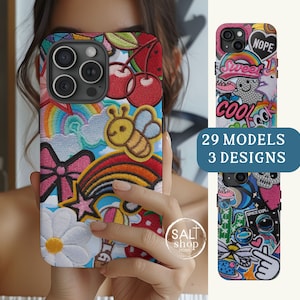 May include: A colorful phone case with embroidered patches, including a rainbow, a bee, a star, a bow, and cherries. The case is designed for an iPhone with a triple camera lens. The text "SALT shop home" is visible in the lower right corner.