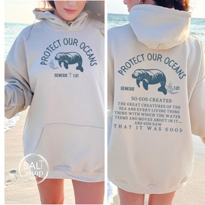May include: A light beige hoodie with a manatee graphic and the text "Protect Our Oceans" with the Bible verse "Genesis 1:21". The back of the hoodie has the same graphic and text with the additional text "So God created the great creatures of the sea and every living thing with which the water teems and moves about in it... And God saw that it was good."