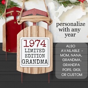 May include: A wooden Christmas ornament shaped like a sled with a red and white sign that reads "1974 Limited Edition Grandma".