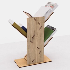 May include: A wooden magazine rack with a tree branch design. The rack has three shelves and is made of light brown wood with dark brown accents. The shelves are angled to hold magazines and books.
