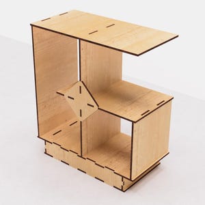 May include: A wooden shelf unit with a unique geometric design. The shelf has four compartments and a top surface. The shelf is made of light wood with a natural finish.