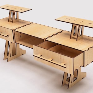 Puede incluir: Una estantería de madera con dos estantes y un cajón. La unidad está hecha de madera clara y tiene un diseño simple y moderno. Los estantes están sostenidos por dos patas a cada lado, y el cajón tiene una manija en la parte delantera.