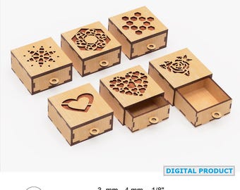 May include: A collection of small, laser-cut wooden boxes with decorative cut-out designs on the lids. The boxes feature various patterns, including a snowflake, a heart, a flower, and geometric shapes. Each box has a small, round pull. The text "DIGITAL PRODUCT" is visible.
