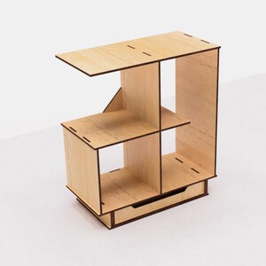May include: A wooden shelf unit with four compartments and a drawer. The shelf is made of light wood with a natural finish. The drawer is made of a darker wood with a brown finish.