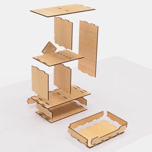 May include: A disassembled wooden shelf unit with six pieces, including a base, three shelves, and two side panels. The shelves are stacked on top of each other, and the side panels are attached to the shelves. The base is a rectangular piece of wood with a small triangular piece attached to the front. The shelves are all the same size and shape, and the side panels are also the same size and shape. The shelf unit is made of light-colored wood.