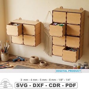 May include: Two wooden storage units with multiple drawers are mounted on a wall. The drawers are open, revealing colorful contents. The units are made of light-colored wood and have a simple, geometric design. The image also includes craft supplies.