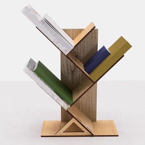May include: A wooden bookshelf shaped like a tree with four shelves. The shelves are filled with books of different colors and sizes. The bookshelf is made of light brown wood and has a triangular base.