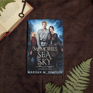 May include: A fantasy novel cover with a dark blue background featuring three people, two women and one man, standing in front of a ship. The title of the book is "Memories of Sea and Sky: Legends of Emyr" by Maegan M. Simpson.