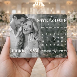 May include: A save-the-date card held in hands, featuring a black and white photo of a smiling couple. The card includes a calendar highlighting May 14, 2026, and the names ERIKK & SAM, with the location MALDIVAS.