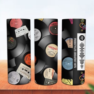 May include: Three black and white insulated tumblers featuring a design of vintage vinyl records and cassette tapes. The tumbler on the right has the text "FREESTYLES GREATEST HITS" and a Spotify logo with a barcode.