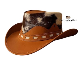 May include: A brown leather cowboy hat with a cowhide crown. The hat features a wide brim and a decorative band with white stitching. The hat is a classic Western style, perfect for outdoor activities or costume events.