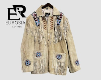 May include: A beige suede leather jacket featuring long fringe detailing across the chest and pockets. The jacket includes colorful beaded circular patches on the sleeves and pockets, brown wooden bead accents, and the text EUROSIAL LEATHER.