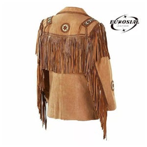 May include: A tan suede jacket with long fringe detailing on the back and sleeves. The jacket features decorative stitching and circular embellishments on the shoulders and back. The EuroSial Leather logo is visible in the upper right corner.