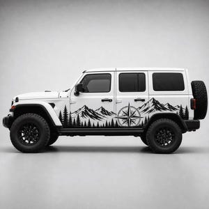 May include: A white four-door SUV featuring a black vinyl decal along the lower side panels. The graphic depicts a continuous landscape of pine trees and mountain peaks, integrated with a large, detailed compass rose design in the center.