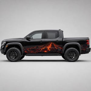 May include: A black pickup truck featuring a large, detailed graphic decal along the side panels. The decal depicts a volcanic mountain landscape with flowing orange and red lava streams against dark, rocky terrain, covering the doors and bed.