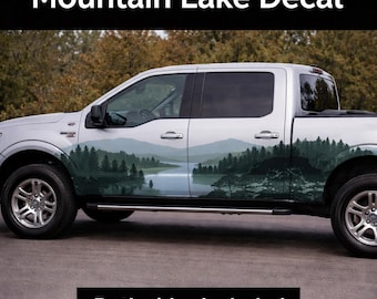 May include: A silver pickup truck with a mountain lake decal on the side. The decal features a scenic landscape with mountains, a lake, and trees in shades of green and blue. Text at the top reads "Mountain Lake Decal" and at the bottom "Both sides included."