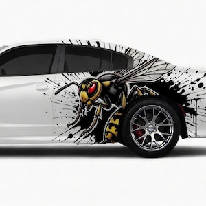 May include: White car with a large graphic of a yellow and black wasp with red eyes. The design includes black paint splatters. The car has black tinted windows and a silver wheel.