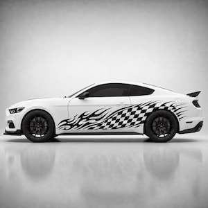 May include: A white sports car shown in profile view, featuring a black and white chequered flag pattern that transitions into stylised black flame graphics along the side panels. The vehicle has black wheels and a rear spoiler on the boot lid.