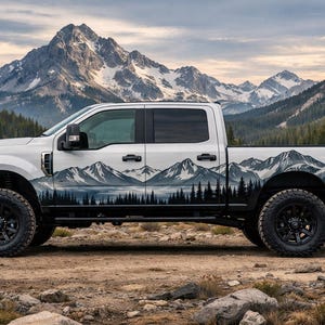 Puede incluir: Una camioneta blanca con un diseño gráfico de montañas y bosques. La camioneta tiene ruedas negras y está estacionada sobre una superficie rocosa. El fondo presenta una cordillera y un lago.
