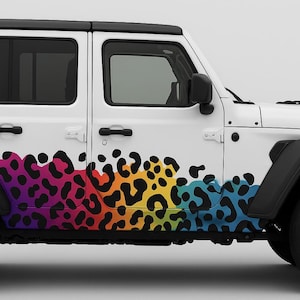 May include: A white Jeep SUV with a black roof and black accents. The side of the vehicle features a colorful leopard print design in shades of purple, red, orange, yellow, and blue.